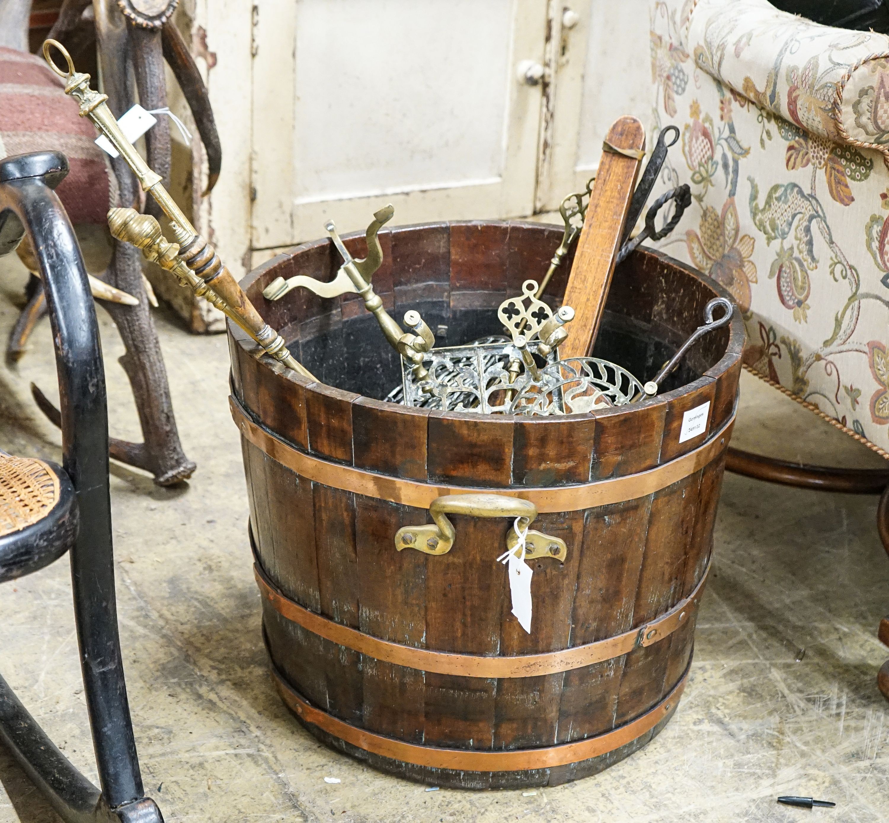 A copper bound staved oak log bin, sundry trivets and fire irons, width over handles 62cm